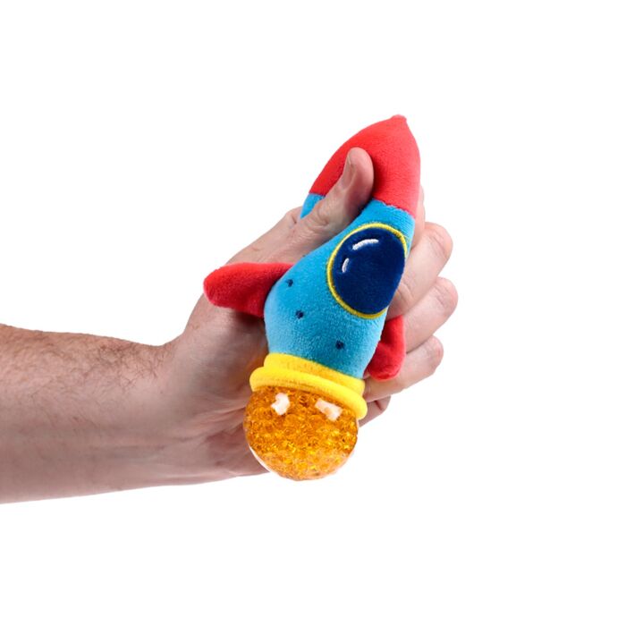 Hand squeezing a blue and red plush rocket Queasy Squeezie causing an orange water bead thruster to bulge out