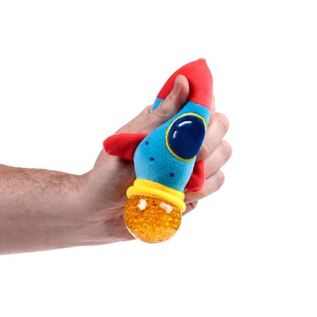 Hand squeezing a blue and red plush rocket Queasy Squeezie causing an orange water bead thruster to bulge out
