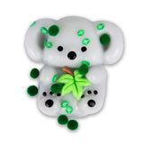 Close-up front view of grey Scrunchems Koala squishy covered in dark green pom-poms, sticky leaf pieces, and eucalyptus sprig
