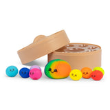 Open Scrunchems dumpling steamer box beside nine colourful kawaii squishy dumpling toys