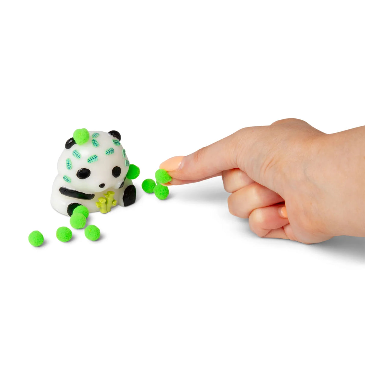 Finger pressing a neon green sticky pom-pom ball onto a white Scrunchems squishy panda