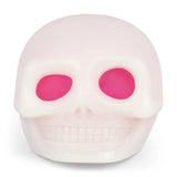 Pale glow-in-the-dark skull squishy with hot pink eye sockets, displayed front-on