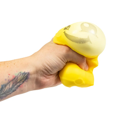 Hand squeezing yellow cheese squishy toy showing inner bubble popping through the top
