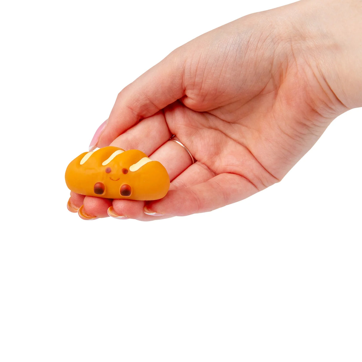 Hand holding an orange iced bun kawaii squishy fidget toy from the Bakery set