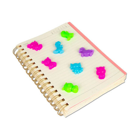 Multiple neon squishy animal figures stuck to the cover of a spiral notebook