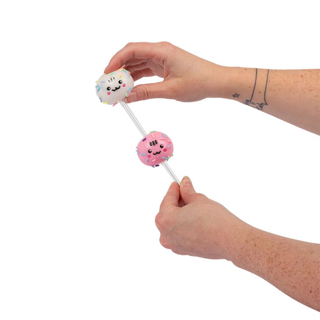 Hands sliding vanilla and pink sticky squishy balls onto Scrunchems Cake Pop stick