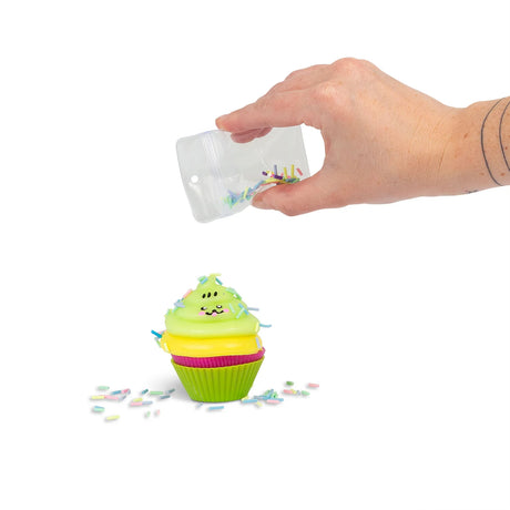 Hand pouring pastel sprinkles onto stacked Scrunchems Sticky Squishy Cupcake with kawaii face