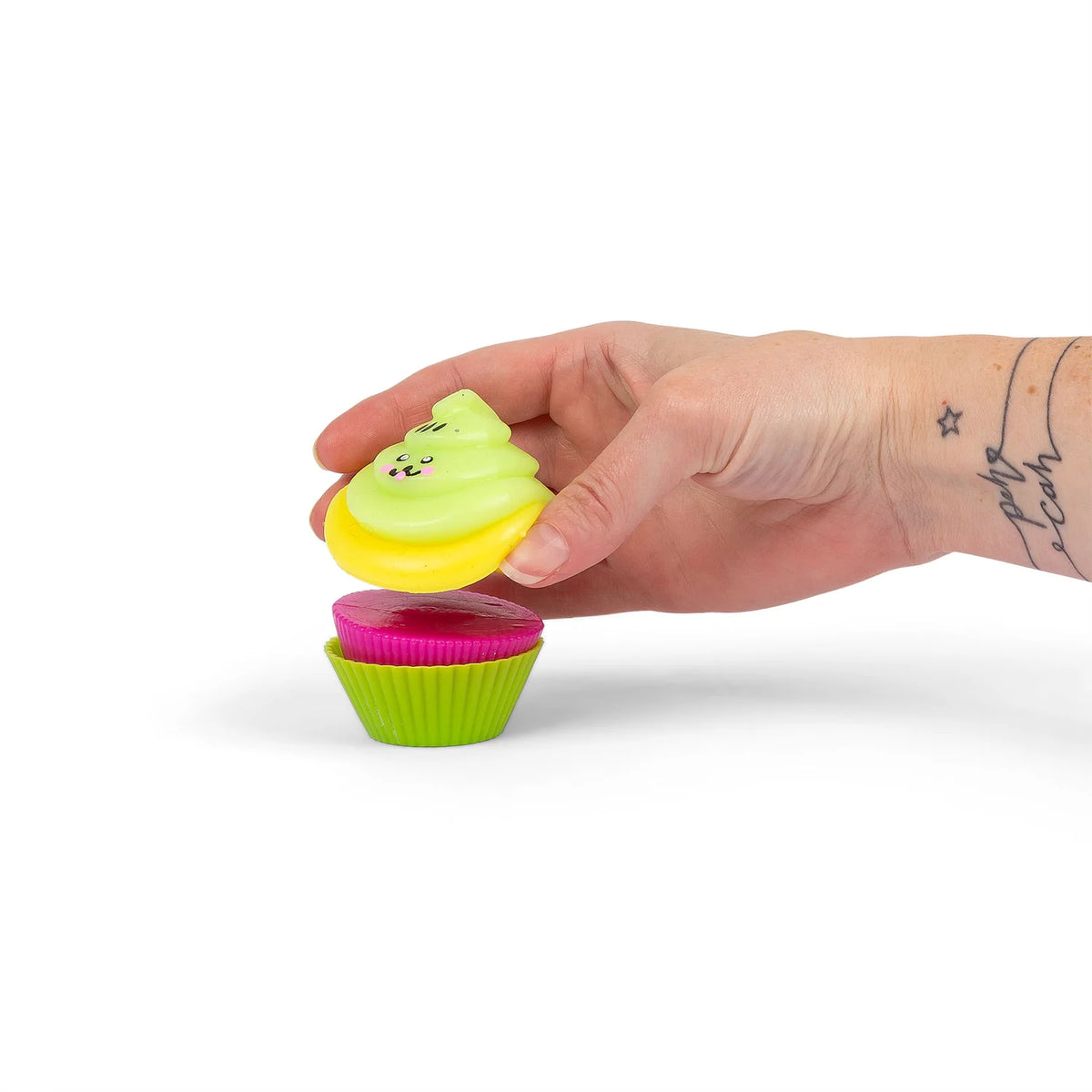 Hand placing kawaii icing onto pink sticky bun in green Scrunchems Sticky Squishy Cupcake case