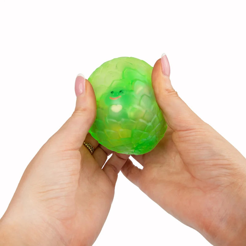 Hands squeezing green Scrunchems Sugar Dragon Egg revealing tiny dragon face inside