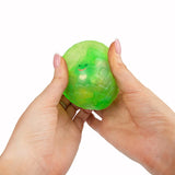 Hands squeezing green Scrunchems Sugar Dragon Egg revealing tiny dragon face inside