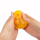 Hands squeezing orange Scrunchems Sugar Dragon Egg revealing dragon face inside shell