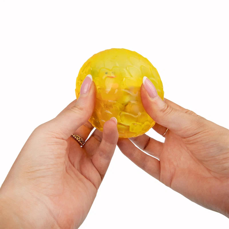Hands squeezing yellow Scrunchems Sugar Dragon Egg showing soft squishy texture
