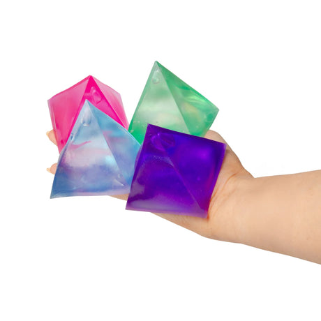 Hand holding four glossy Scrunchems Sugar Pyramid squishy toys in pink, blue, green and purple
