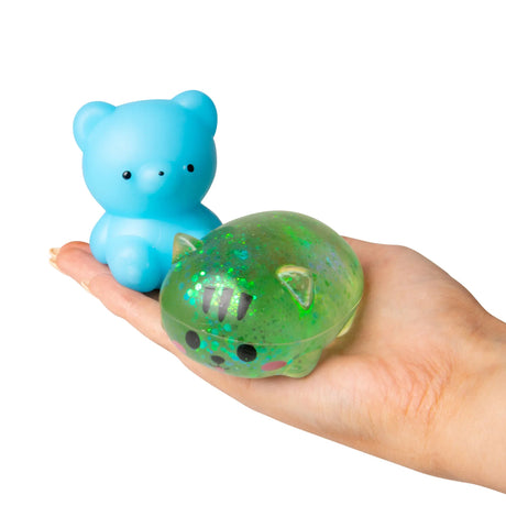 Blue squishy bear and green glitter squishy kitty from Scrunchems Surprise Box resting on an open palm