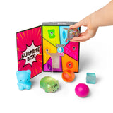 Hand removing a confetti ball from open Scrunchems Surprise Box surrounded by five other revealed squishy toys