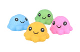 Four kawaii-style squishy octopus squeeze toys in blue, yellow, green, and pink, each with a smiling face, arranged in a loose cluster against a white background
