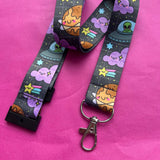 Full length Space Cuties kawaii lanyard laid out on a pink background showing the full space print with planets, aliens, stars and clouds