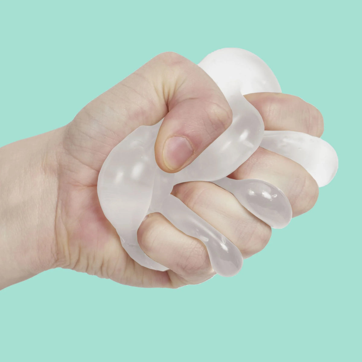 Hand squeezing a white Speks Gump Ghost squishy toy between fingers on a teal background