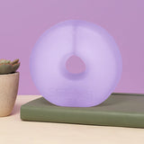 Lilac translucent Speks Gump Jumbo Loop standing upright on a desk beside a plant and book