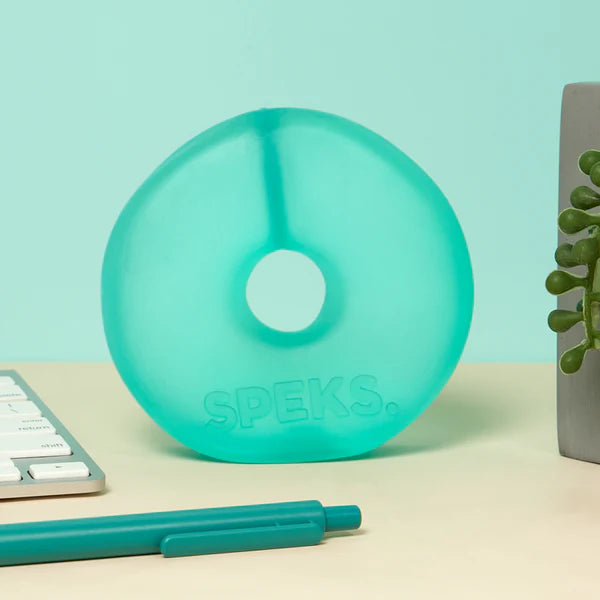 Mint green translucent Speks Gump Jumbo Loop standing upright on a desk beside stationery