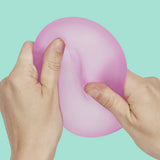 Two hands squeezing and deforming pink Speks Gump Jumbo Loop fidget toy