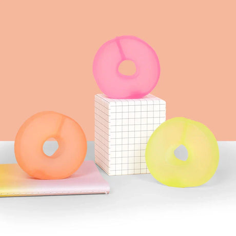 Pink, peach and lime Speks Gump Loop memory gel fidget rings displayed on a desk