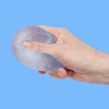 Hand squeezing a pale blue Speks Gump Surface memory gel stress ball against a blue background