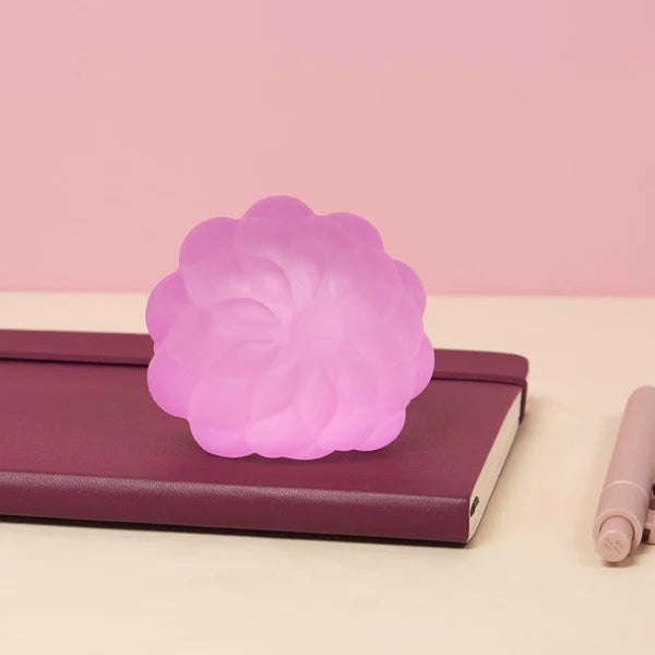 Pink Speks Gump Surface stress ball resting on a notebook beside a pen on a desk
