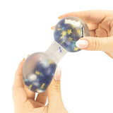 Two hands squeezing the Squeeze Pops Space toy at each end, showing the glitter and star scene transferring between spheres