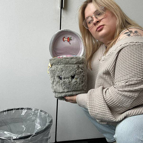 Squishable Mini Trash Can collectible plush held open by woman next to real bin