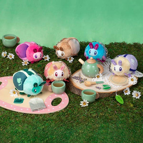 Plush toys resembling animals in a tea party setting on a grassy surface with a green background.