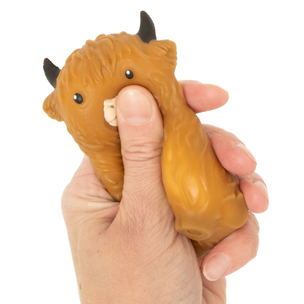 Hand squeezing dark brown Squishy Highland Cow showing slow rise stress relief sensory fidget toy texture