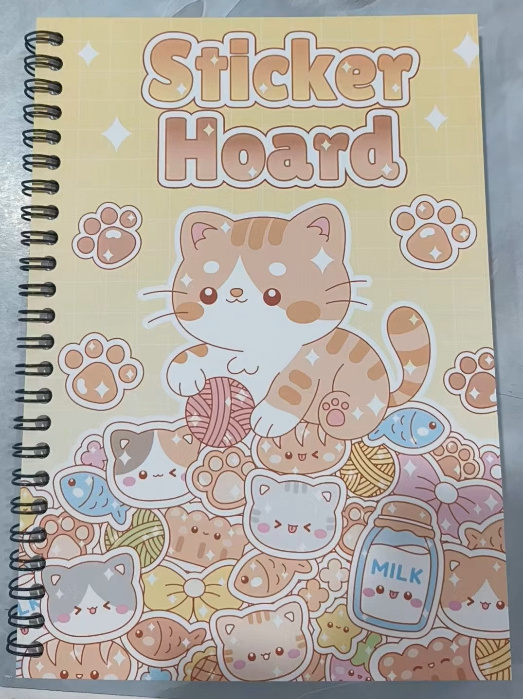 Kawaii Sticker Hoard spiral book with tabby cat and yarn ball cover design on yellow background