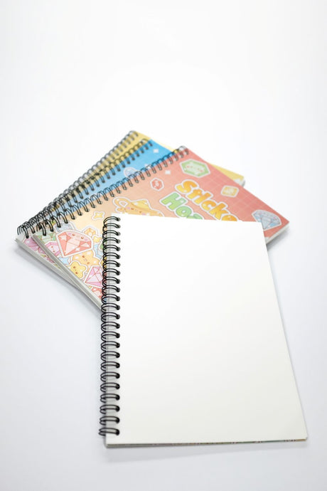 Four Sticker Hoard reusable sticker books fanned out showing blank glossy pages