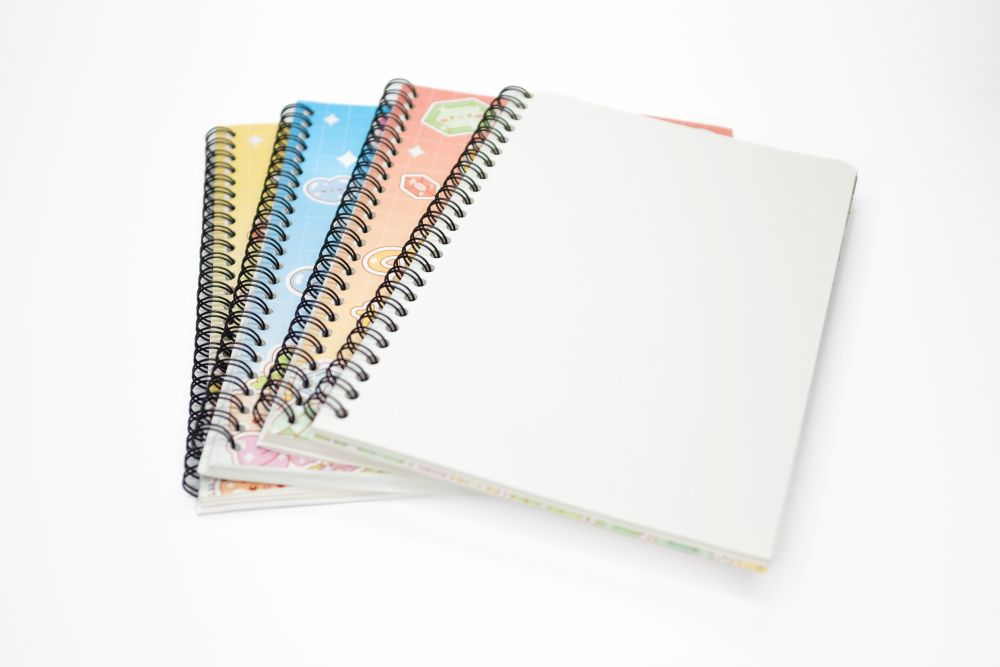 Four Sticker Hoard reusable sticker books fanned open showing spiral binding and pages