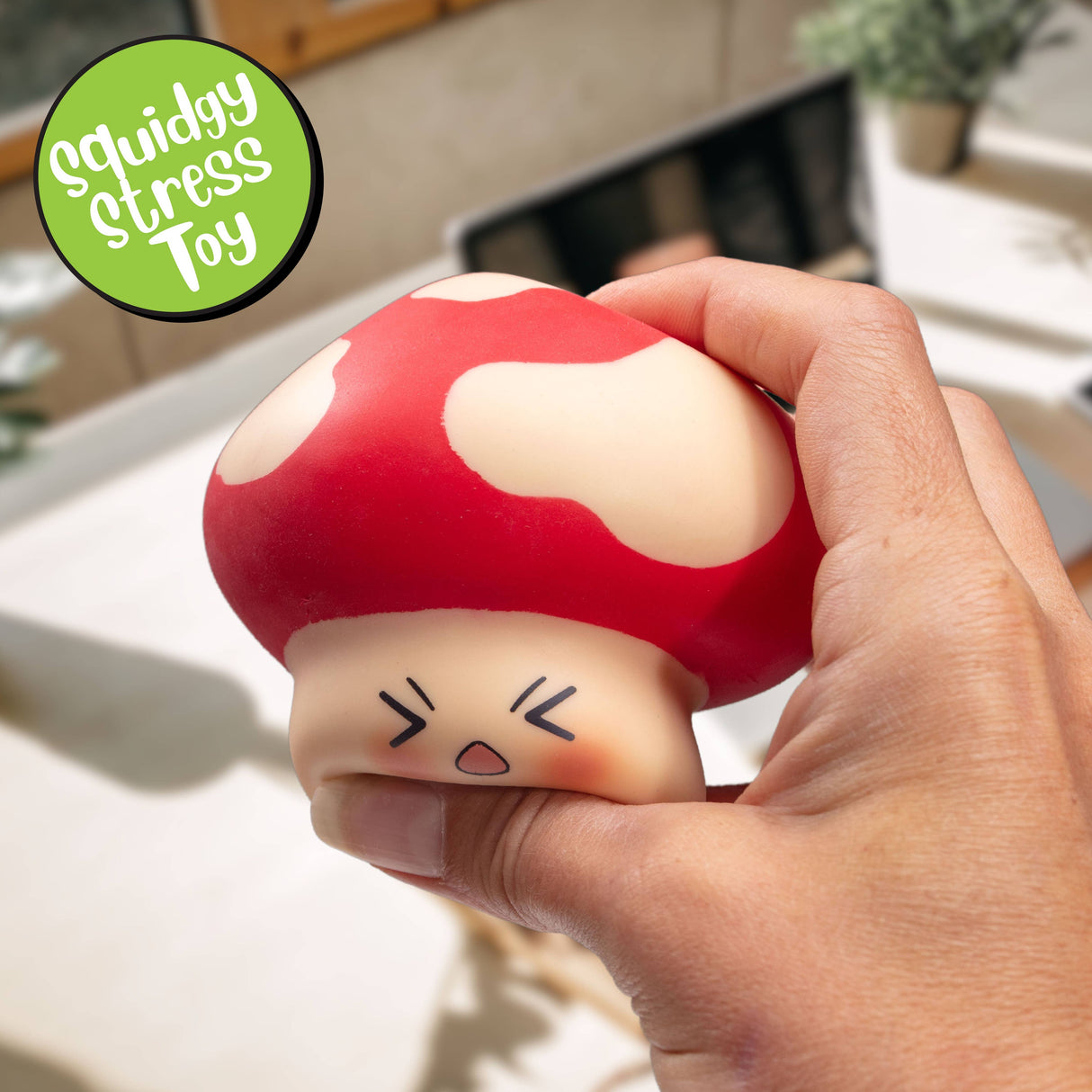 Hand firmly squeezing the red kawaii Stress Shroom mushroom squishy
