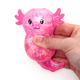 Hand squeezing a pink glitter axolotl squishy sensory fidget toy for stress relief