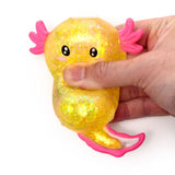 Hand squeezing a yellow glitter axolotl squishy sensory fidget toy for stress relief