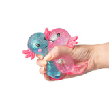 Hand squeezing blue and pink large glitter gel Sugar Axolotl squishies together