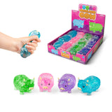 All four Sugar Highland Cow glitter squishies in green, pink, purple, and blue shown with branded display box