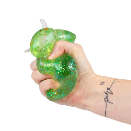Hand squeezing a green glitter Sugar Sea Sheep squishy fidget toy from above, showing deformation