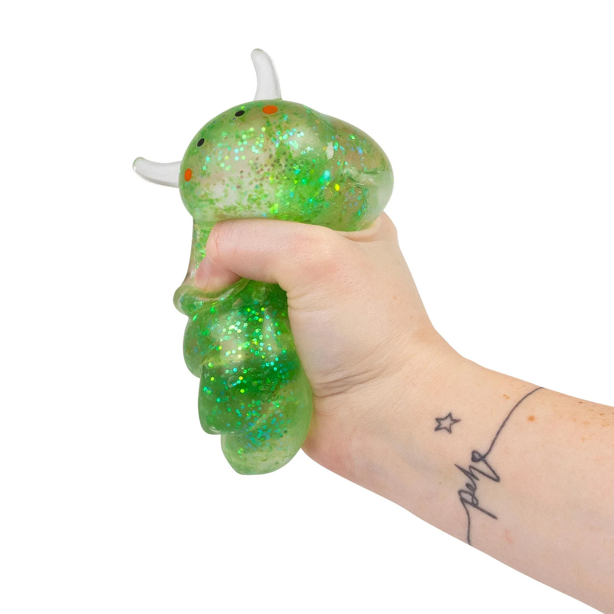 Hand squeezing a green glitter Sugar Sea Sheep squishy fidget toy from the side, showing full squish