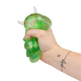Hand squeezing a green glitter Sugar Sea Sheep squishy fidget toy from the side, showing full squish