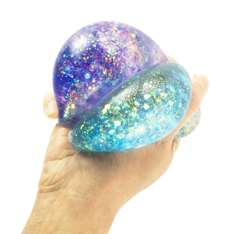 Hand squeezing Super Squidge Galaxy Glitter Ball showing purple and blue holographic glitter swirling inside