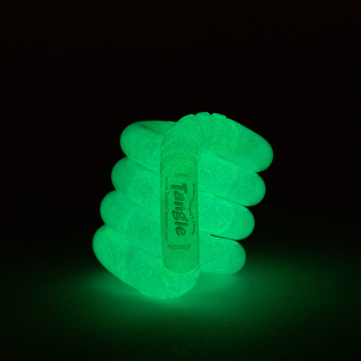 Blue glow-in-the-dark Tangle Jr. twisted fidget toy glowing bright aqua in the dark