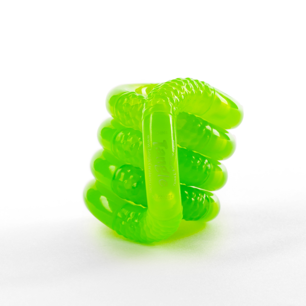 Green glow-in-the-dark Tangle Jr. fidget toy with scaly textured segments, coiled into a stack
