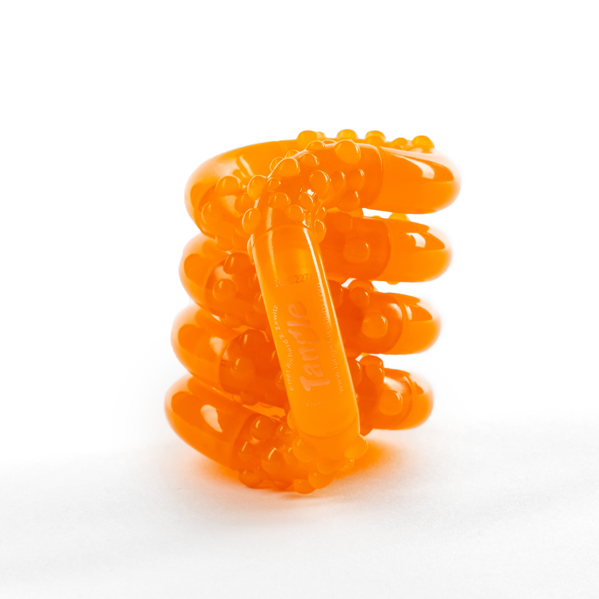 Orange glow-in-the-dark Tangle Jr. fidget toy with bumpy textured segments, coiled into a stack