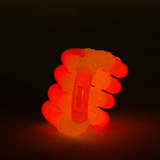 Pink glow-in-the-dark Tangle Jr. ribbed fidget toy glowing red and orange in the dark