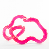 Pink glow-in-the-dark Tangle Jr. ribbed twisty fidget toy twisted into a flowing wavy shape