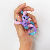 Hand holding a purple and blue cat Tangle Jr. Pet fidget toy wrapped around fingers